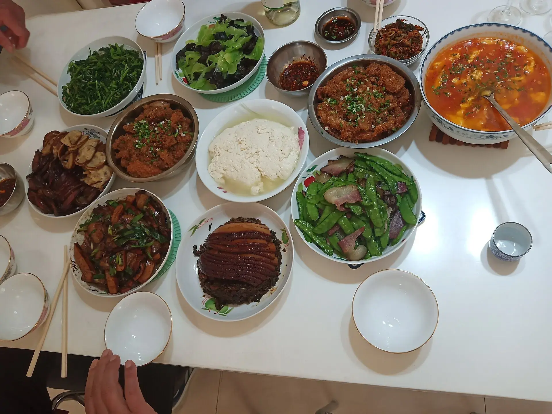 A table crowded with Sichuan home-style dishes