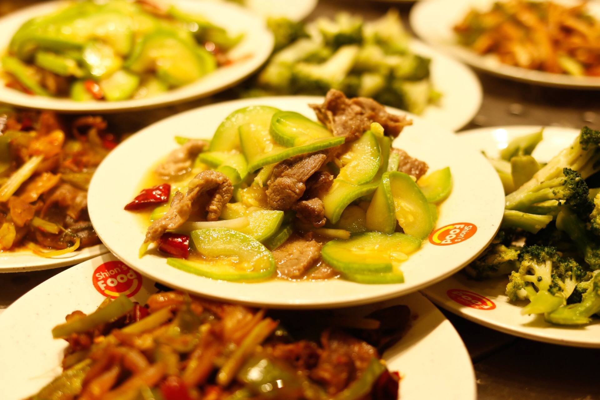 A table of home-style dishes, zucchini and beef in the middle