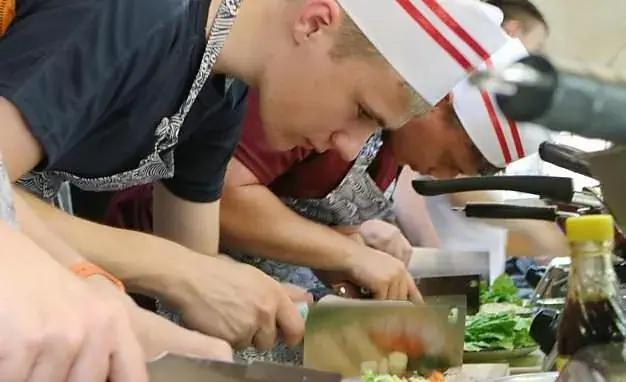 A chef guiding a guest through knife work