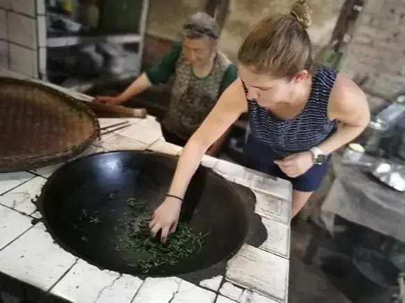 A guest turning tea leaves in a hot wok