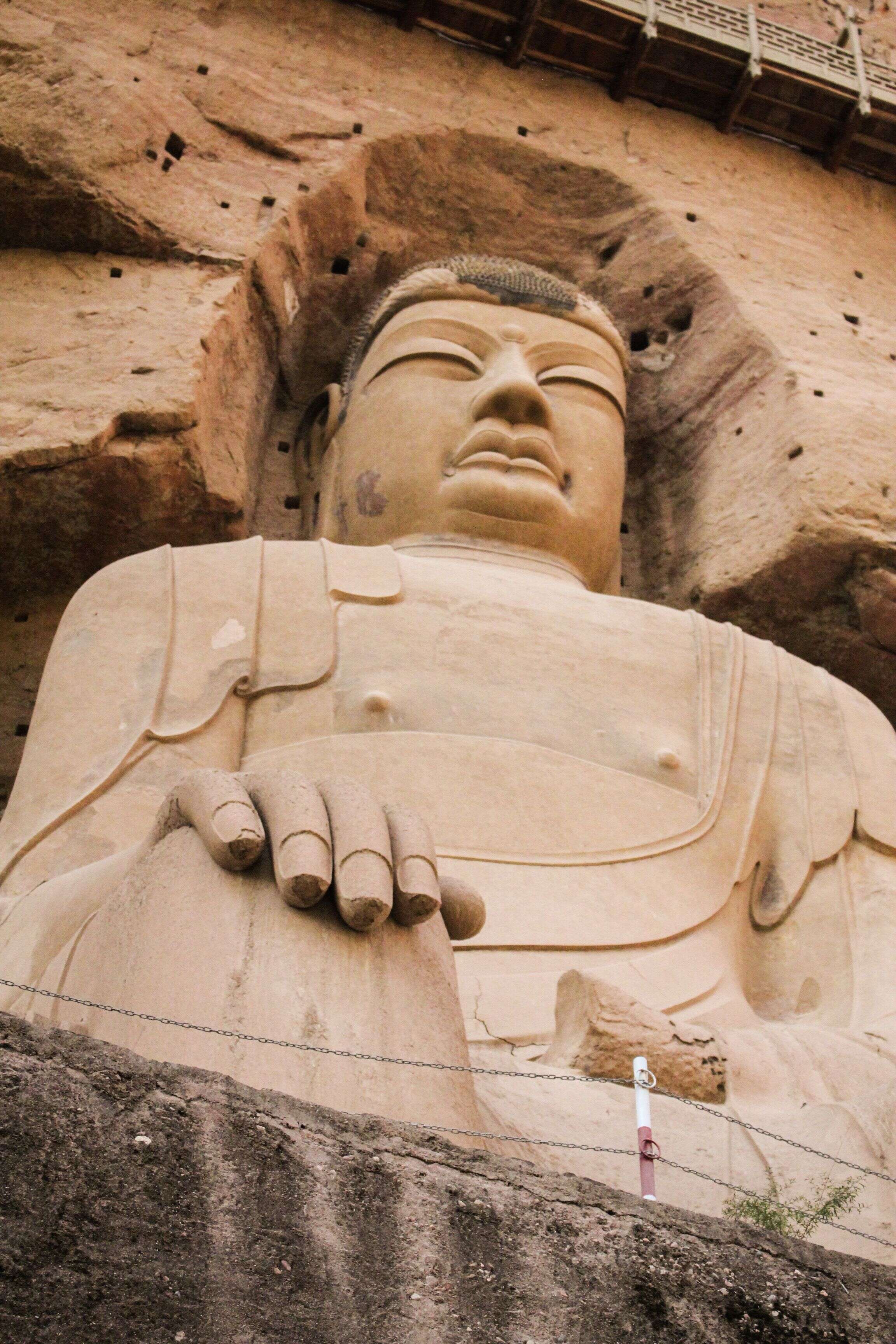 从崖壁栈道仰望乐山大佛的面庞与手