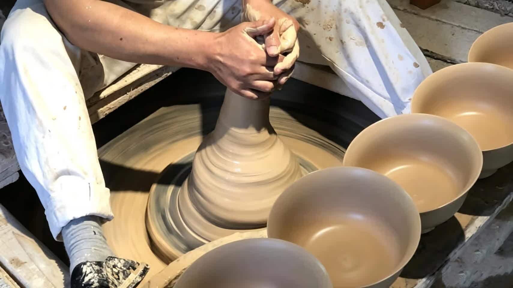 A pair of hands throwing clay on a potter's wheel