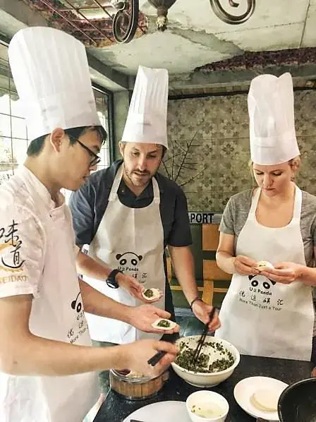 A chef and guests around a work table in the cooking school