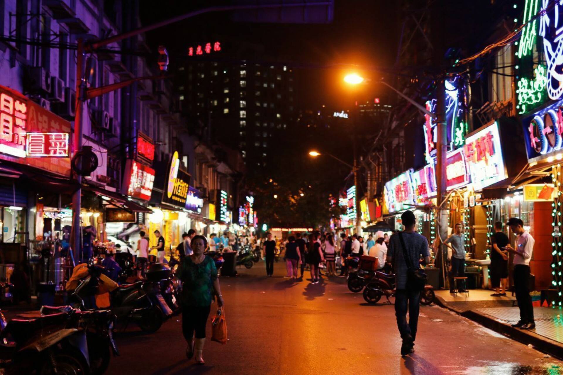 A food street at night, neon signs and scooters