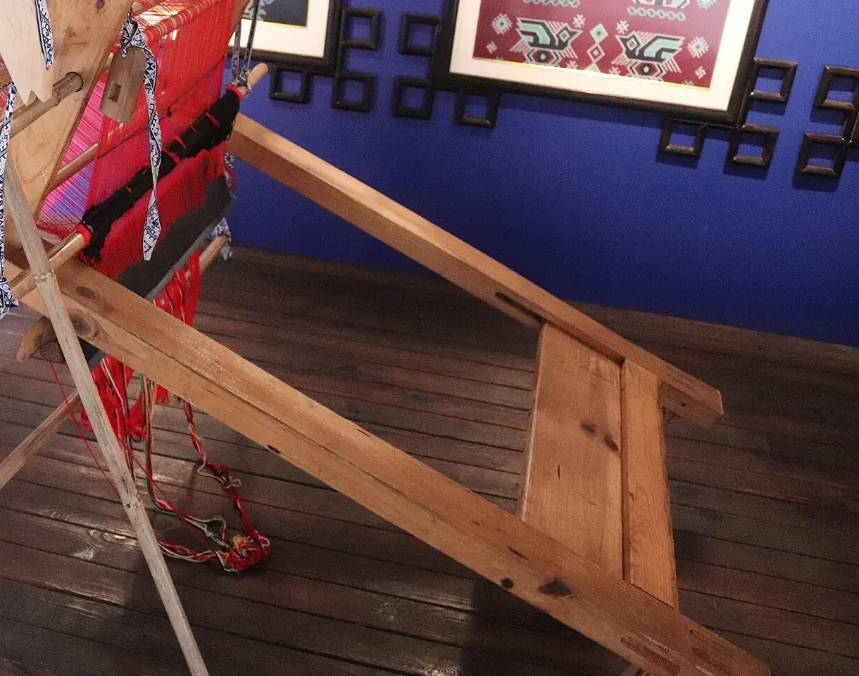 The loom and the plain wooden bench you sit on to work it
