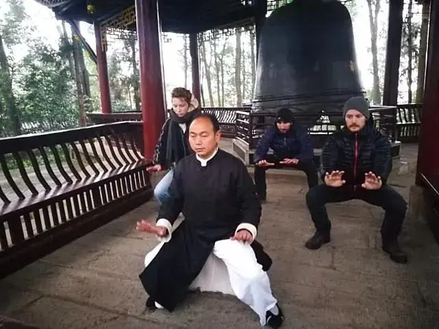 A kungfu master demonstrating while guests watch from the pavilion