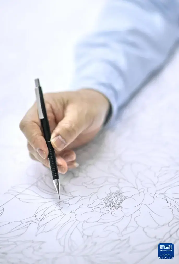 A hand drawing a design on paper