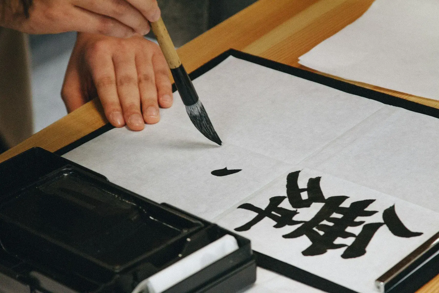 A hand writing characters with a brush on paper