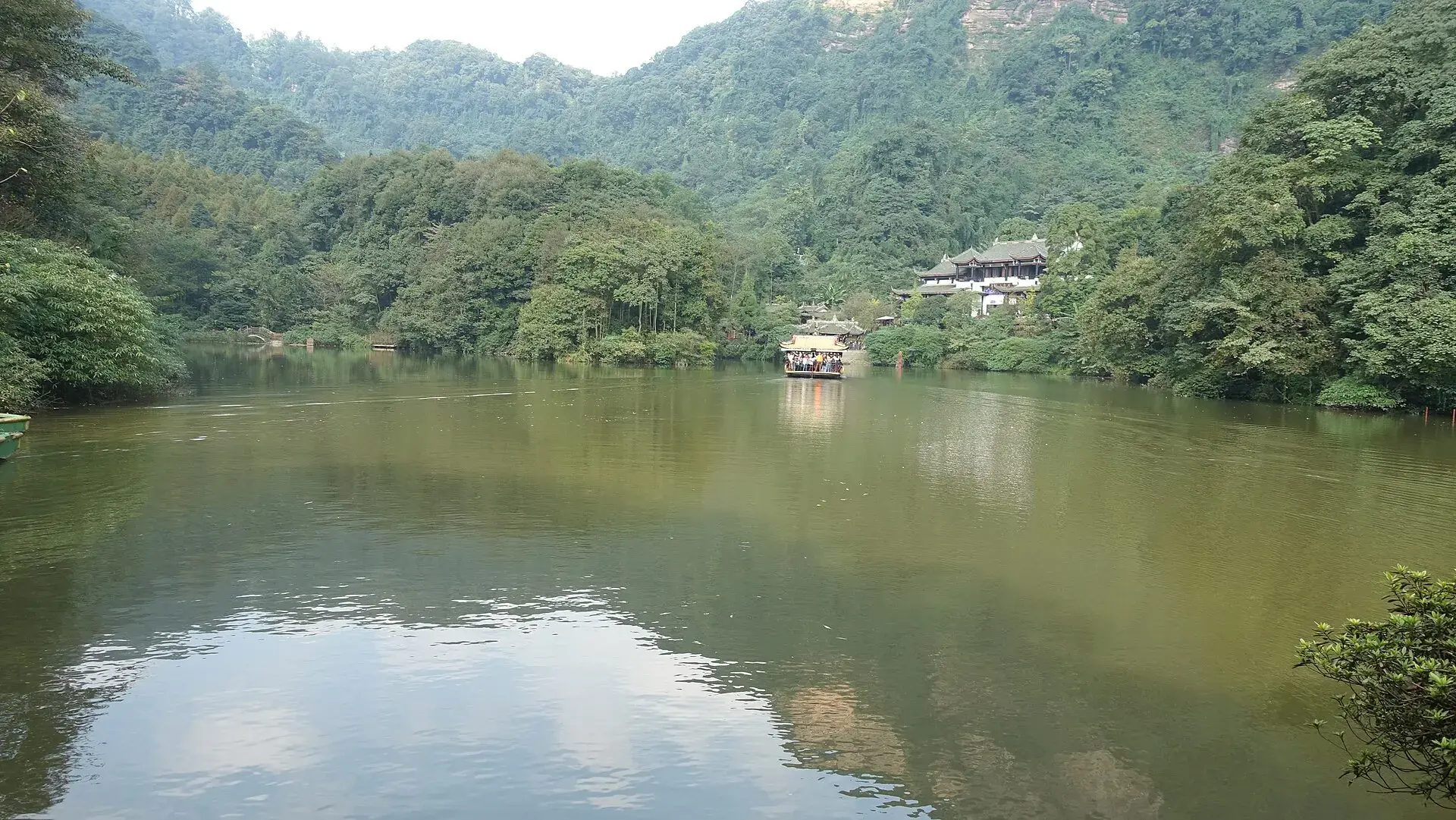 Forested hills above still water on the quiet side of the mountain