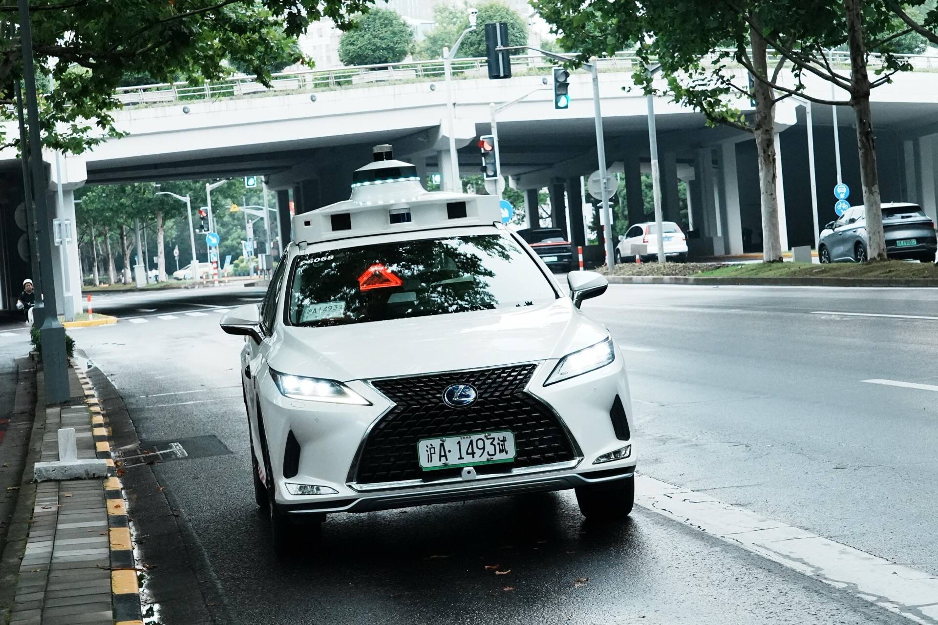 A white test car with a roof sensor stopped under an elevated road