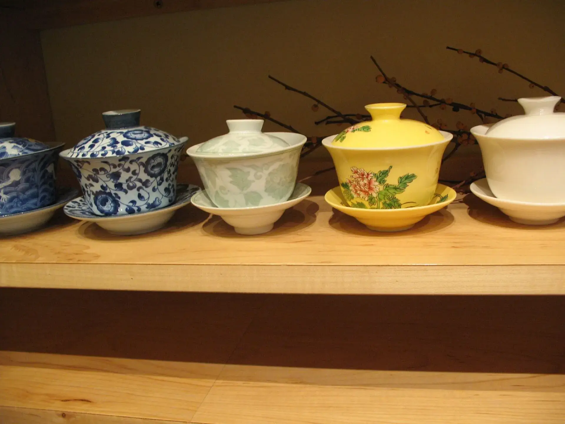 A row of lidded gaiwan cups on a wooden shelf