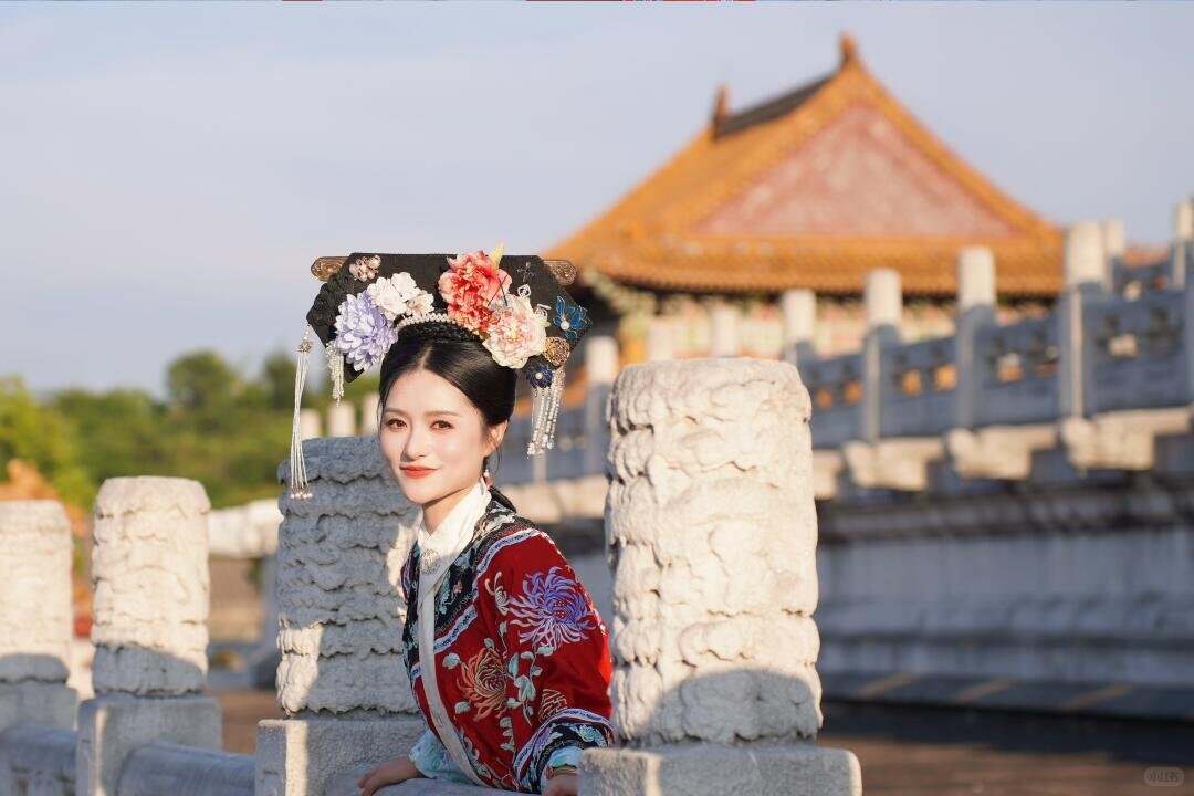 A visitor in Qing court dress glancing back beside a bridge railing in the palace grounds