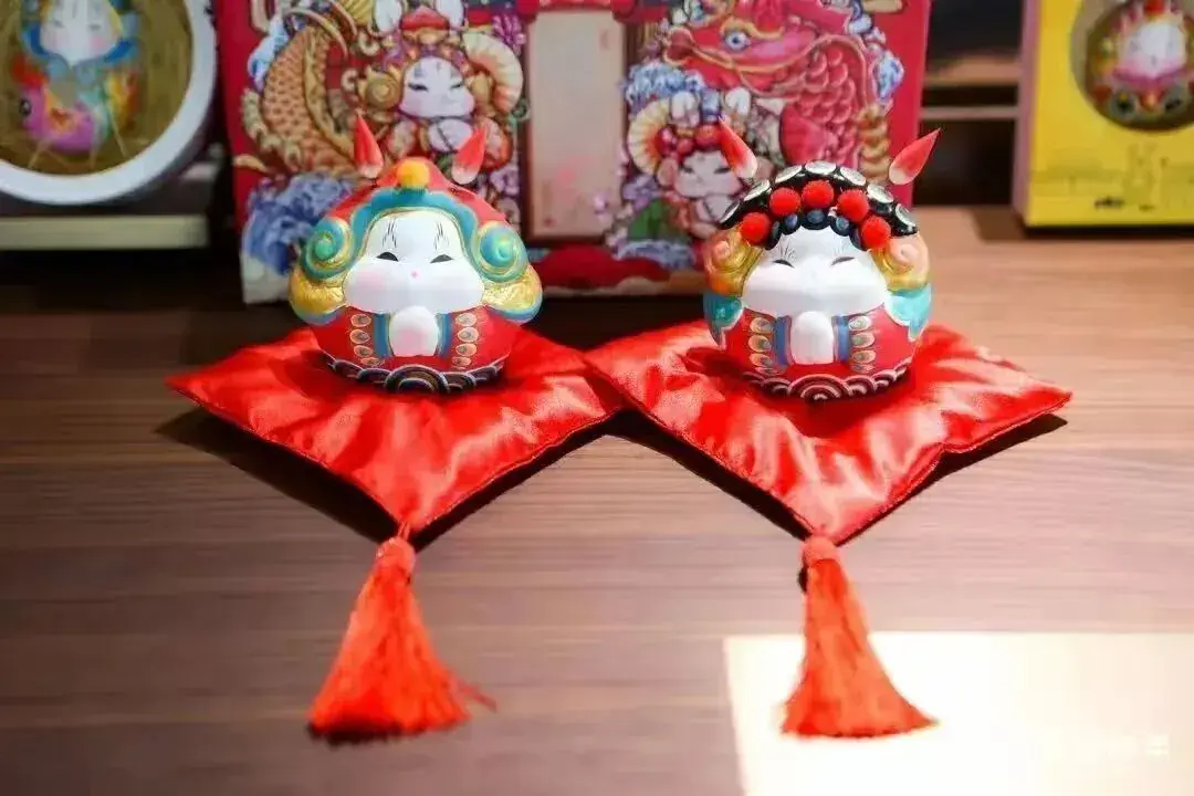 A pair of Tu'er Ye figures on red stands