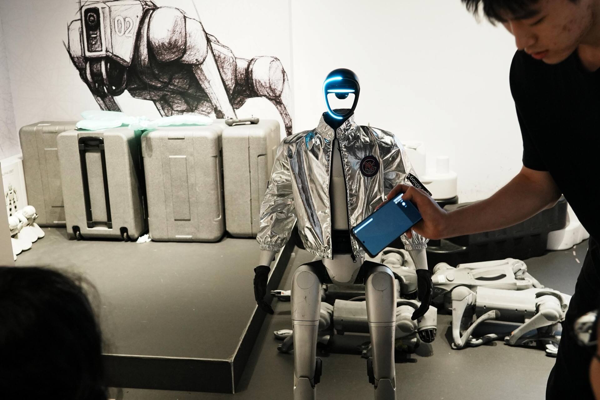 A visitor holding a phone up to the humanoid robot