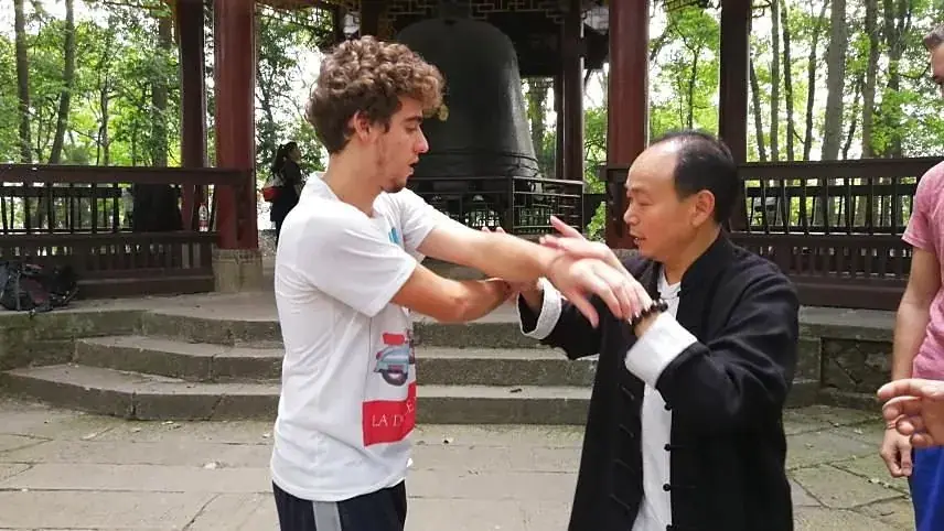 A kungfu master teaching a guest one to one beside the monastery bell