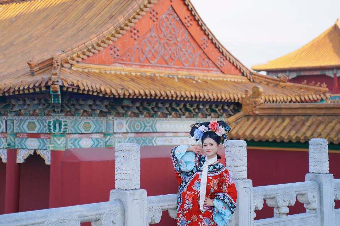 A visitor in Qing court dress standing beside the white marble balustrade of the Palace of the Ming and Qing Dynasties