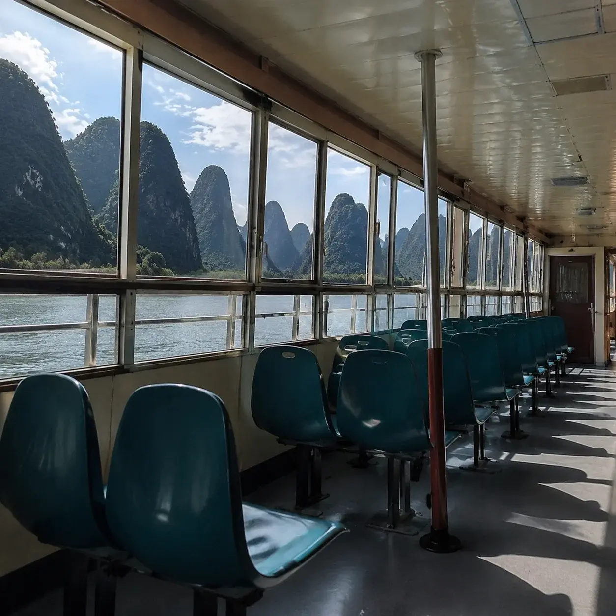 Seating and panoramic windows inside a Li River cruise boat