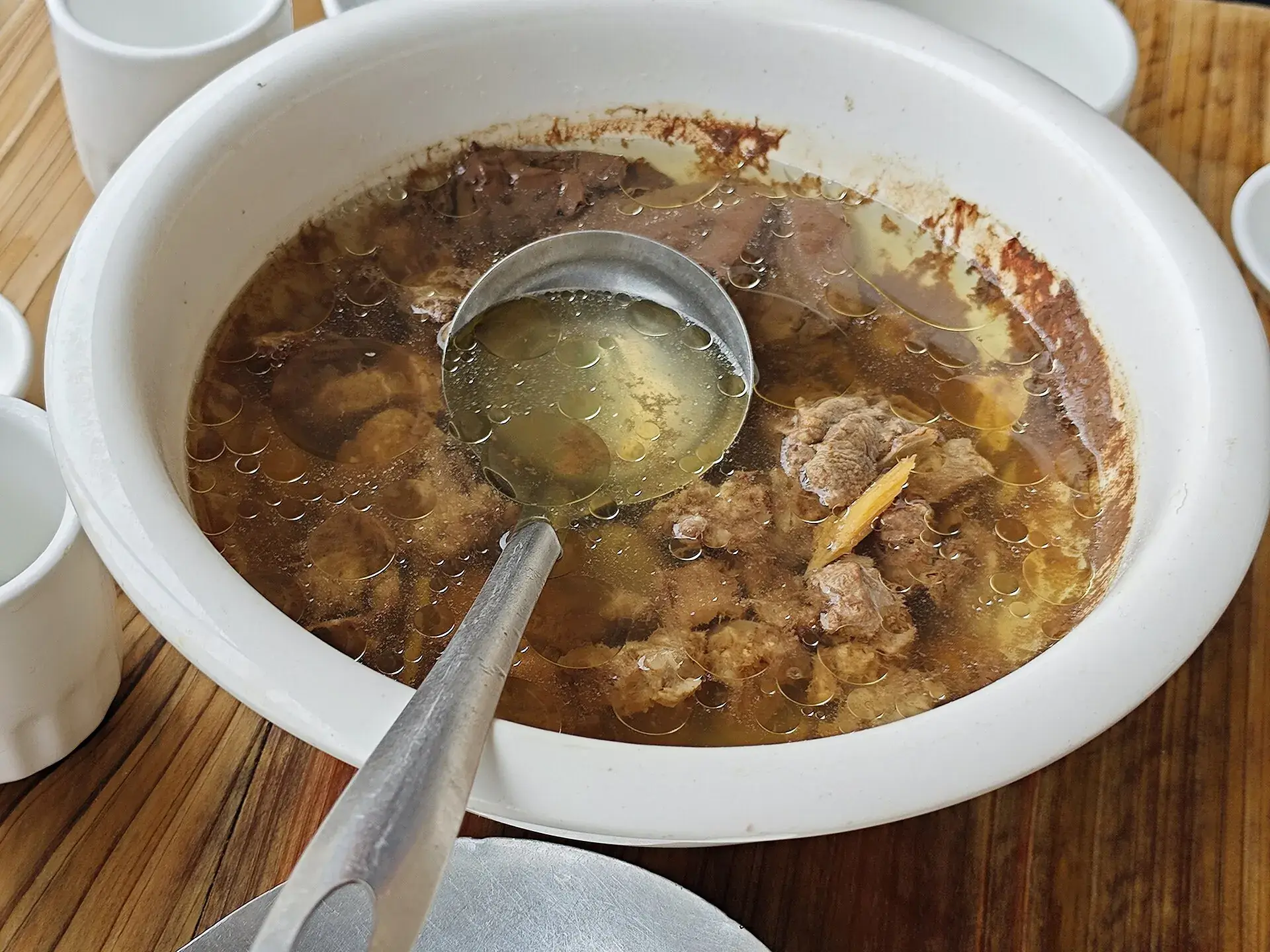 A clear stewed soup ladled from a white pot