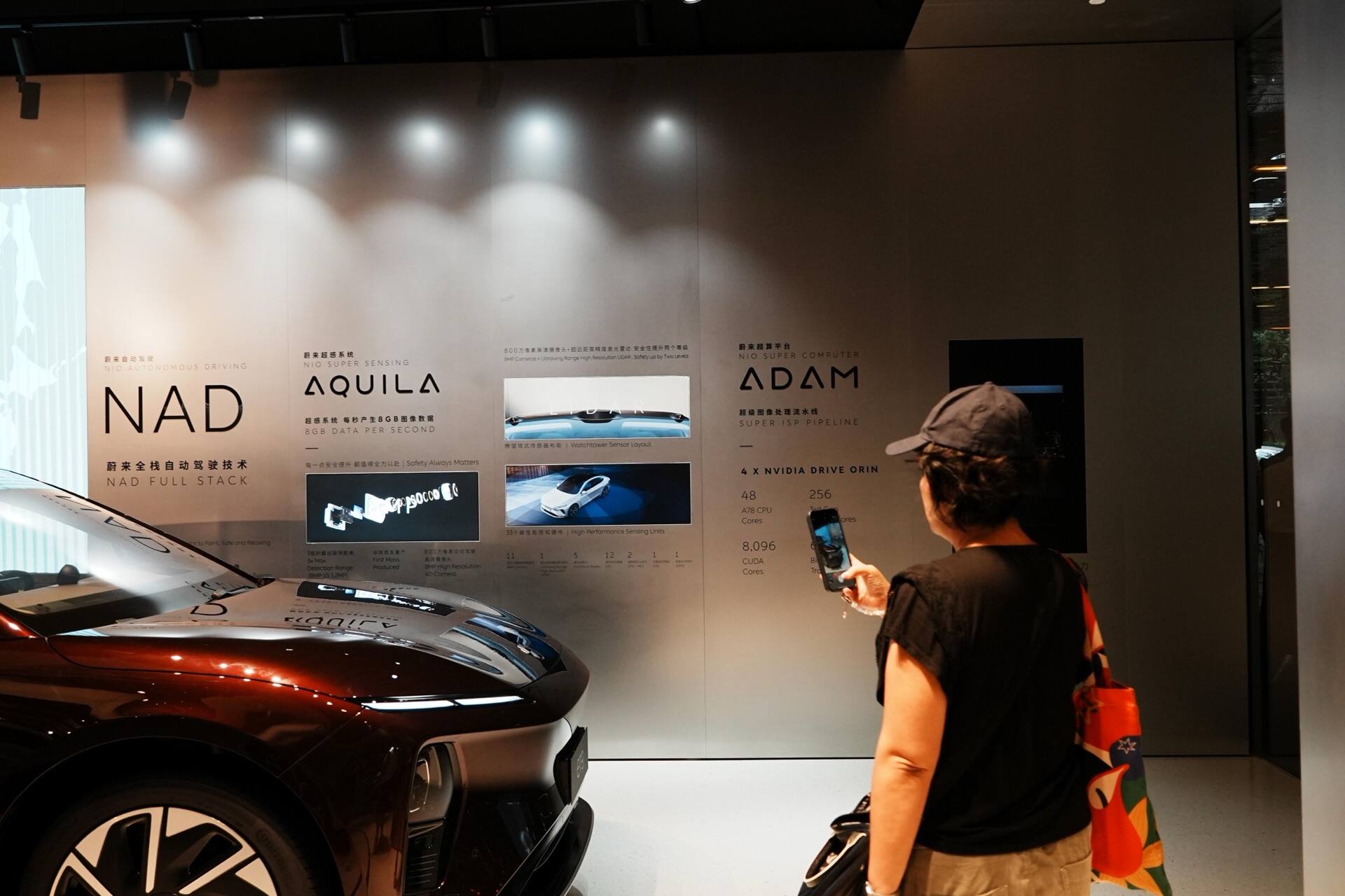 A visitor photographing the autonomous-driving wall in a NIO showroom