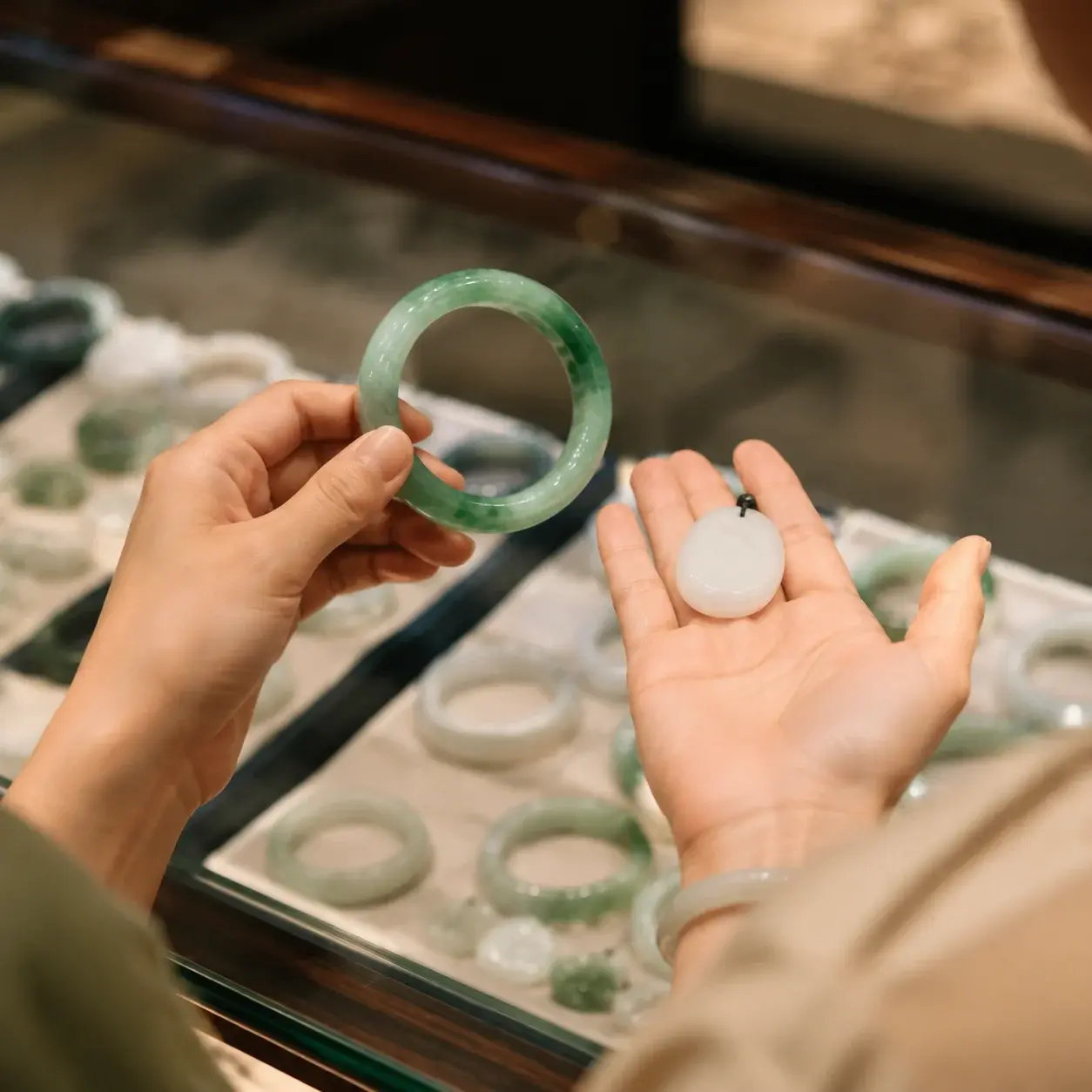 A traveler compares a green jade bangle and a white jade pendant inside a Chinese jewelry shop