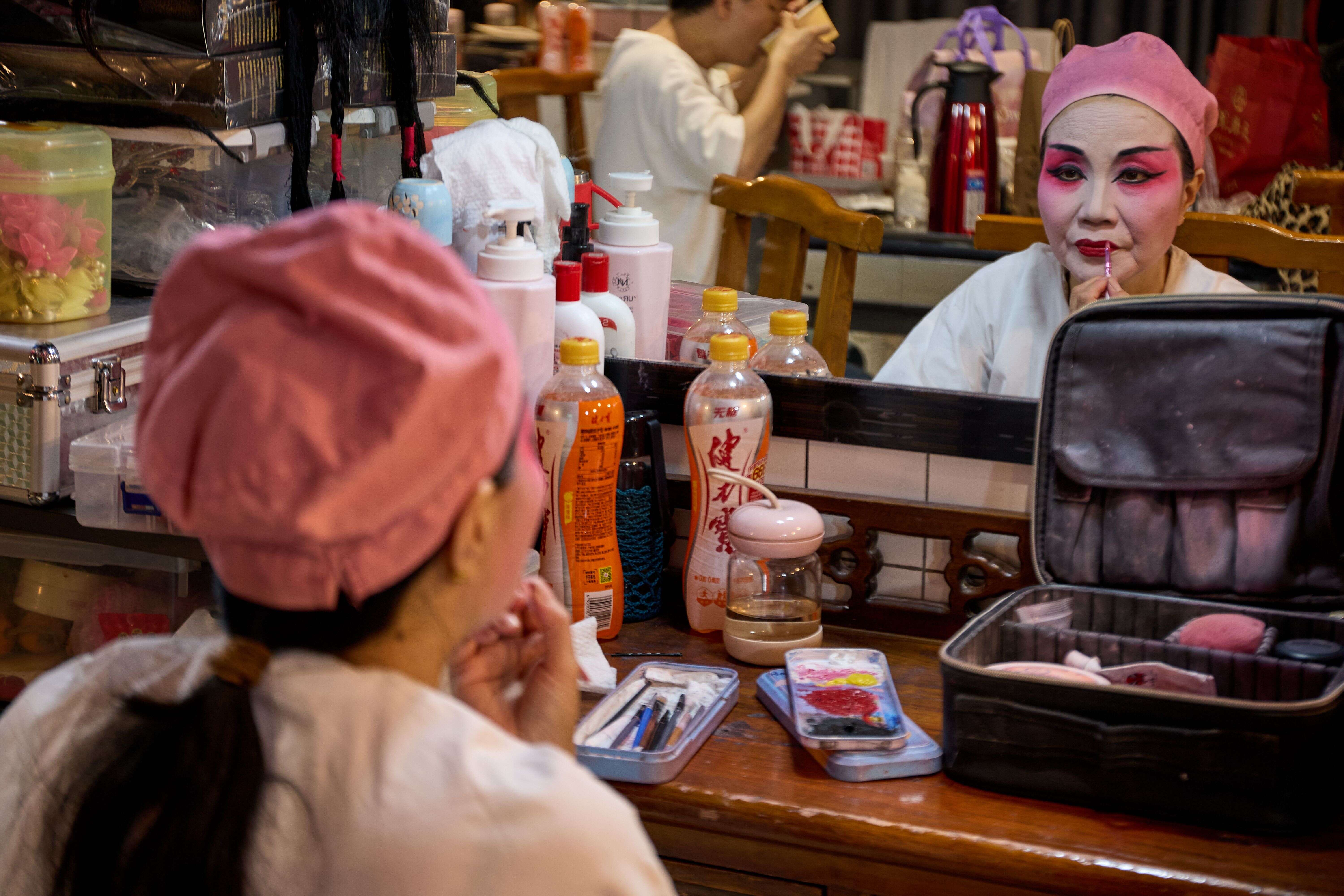 Backstage dressing table at a Sichuan opera teahouse, makeup brushes, face paint, an old mirror
