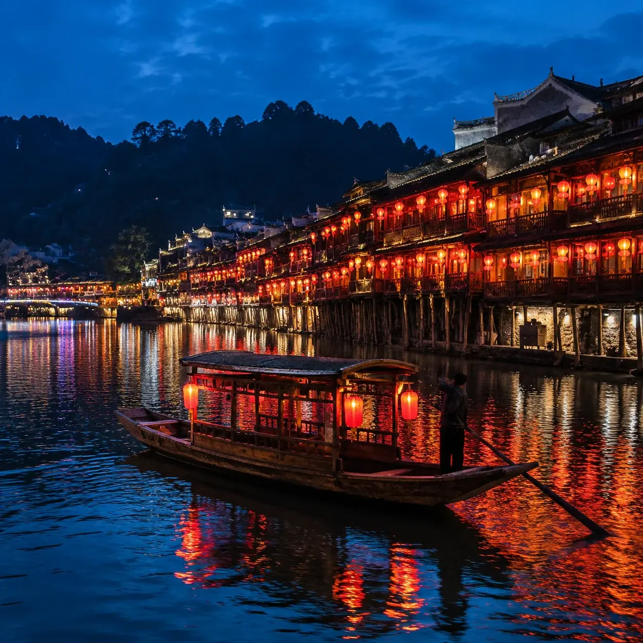 A night cruise boat on the Tuo River beneath lantern-lit stilt houses in Fenghuang