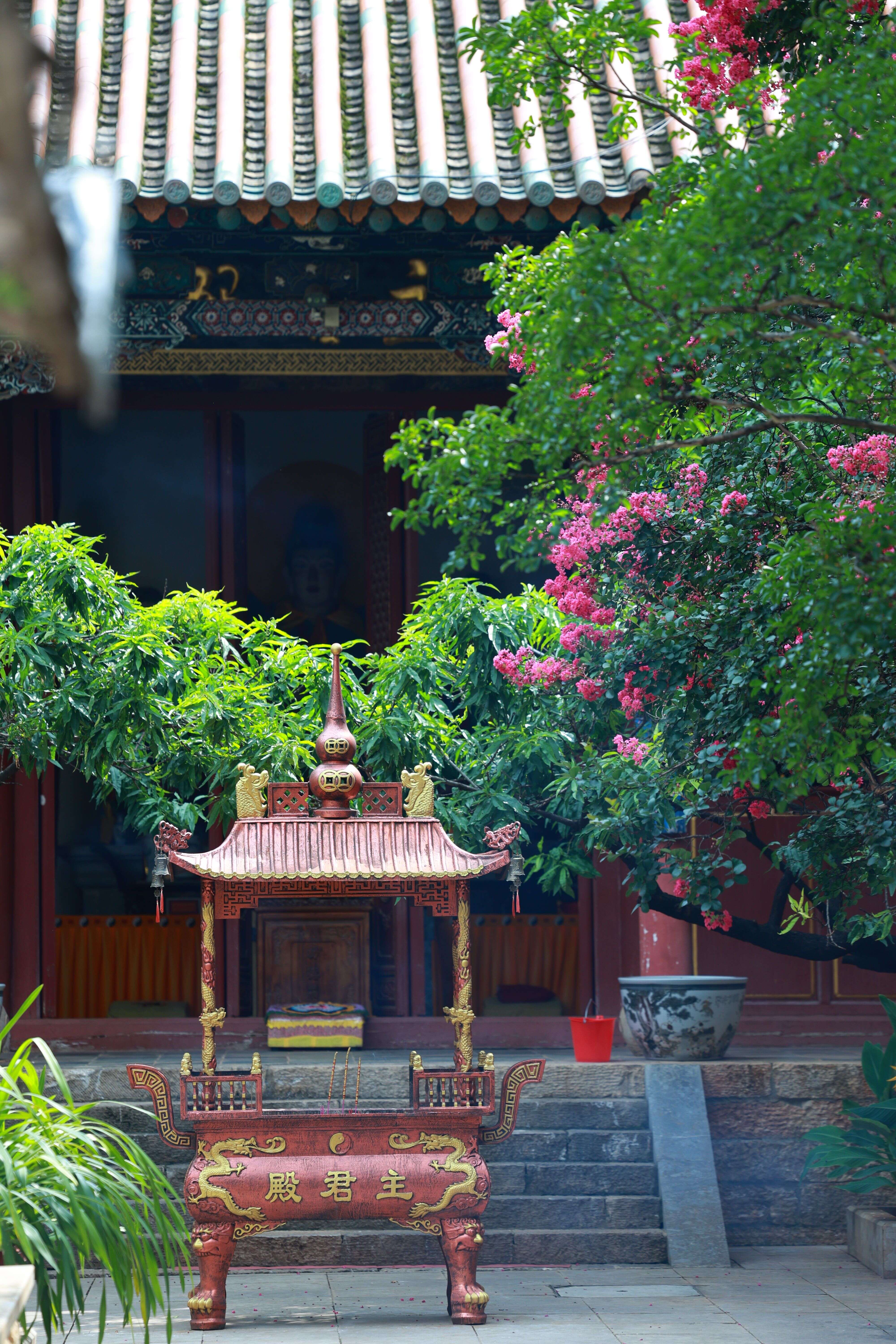 Incense in a working Taoist courtyard, trees around the hall
