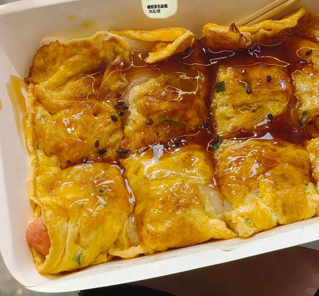 A box of egg-wrapped mochi with sweet-and-sour sauce poured over it