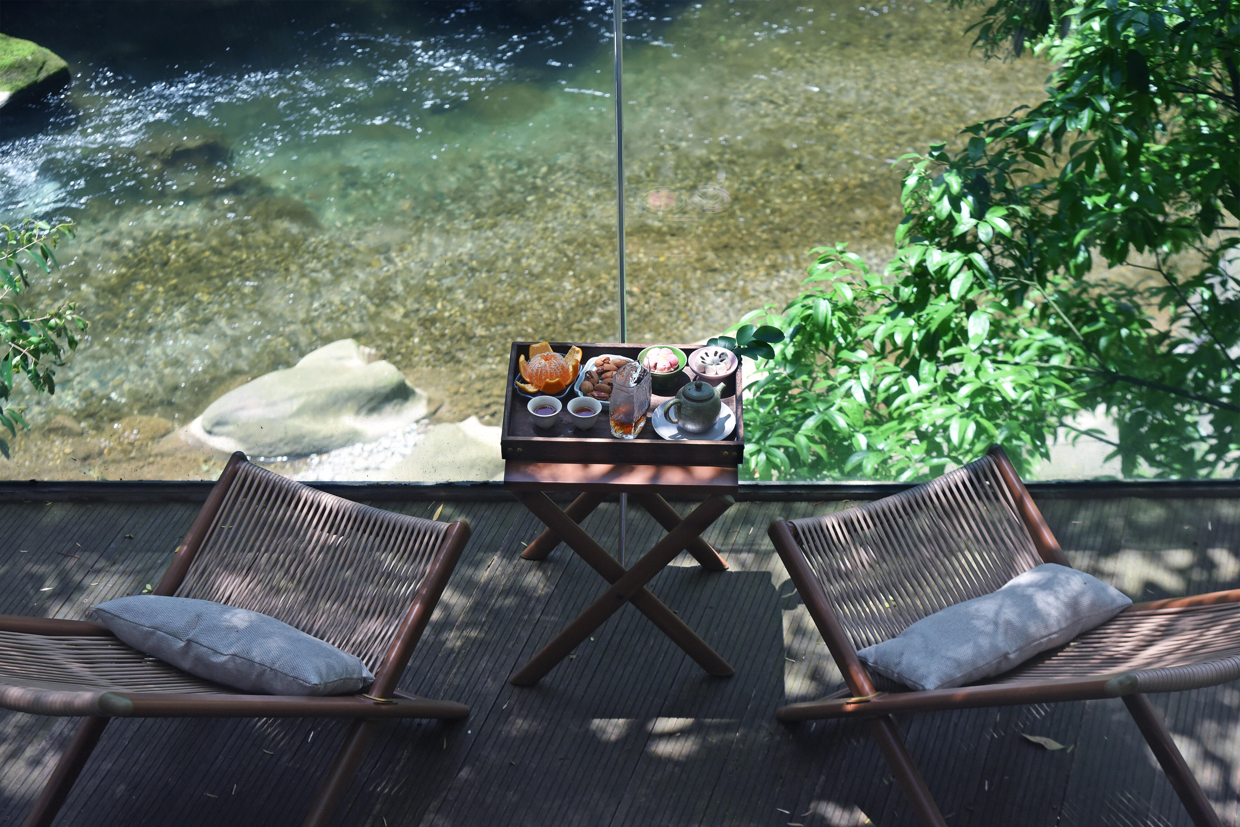 A tea tray with pot and cups beside a mountain stream