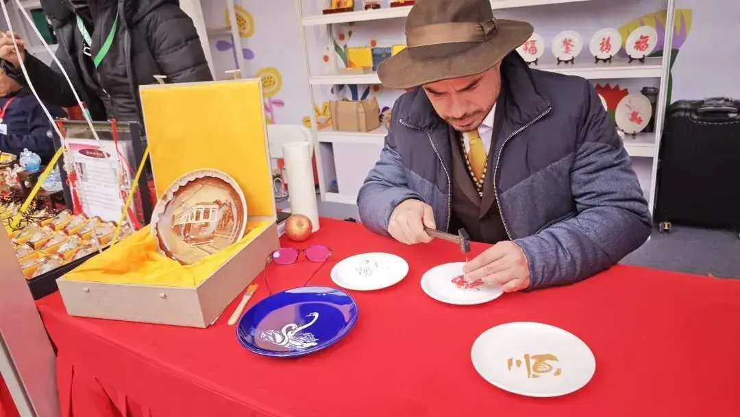 A maker demonstrating Tu'er Ye painting at a red-covered table