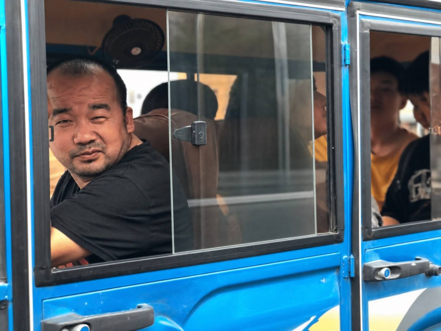A tuk-tuk driver at the window of his blue cab