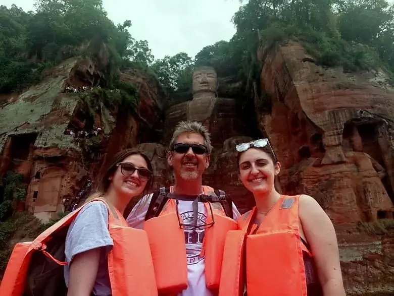 Guests in life jackets on the boat with the Giant Buddha behind them