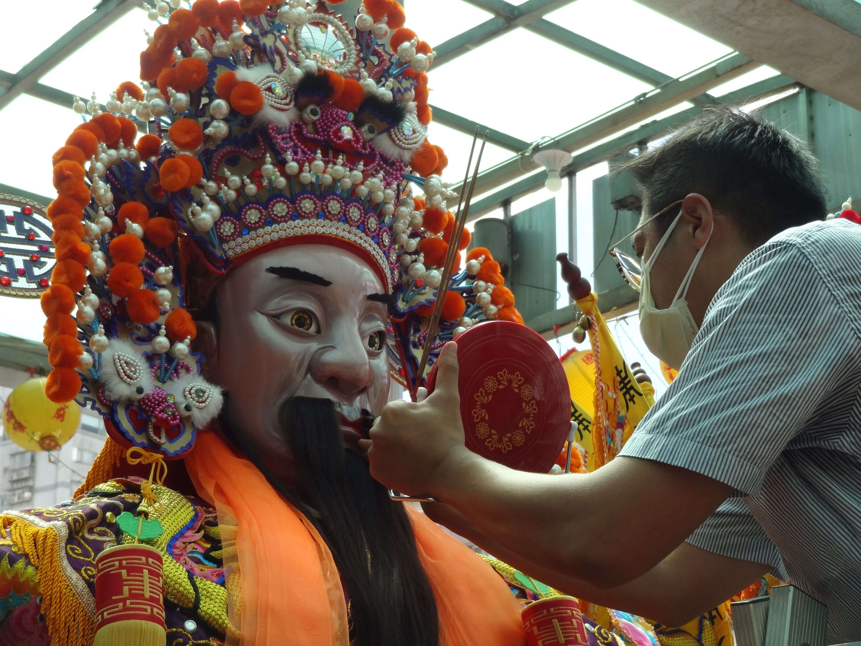 Two Sichuan opera performers painting eye makeup at a cluttered backstage table