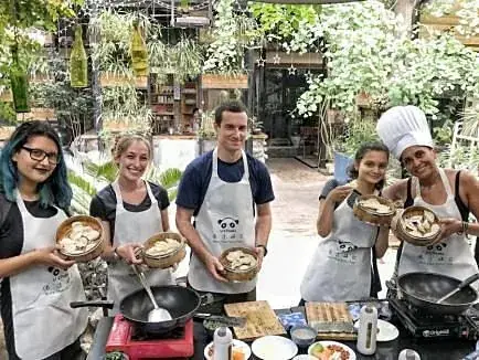 Guests in aprons with their woks in the garden kitchen
