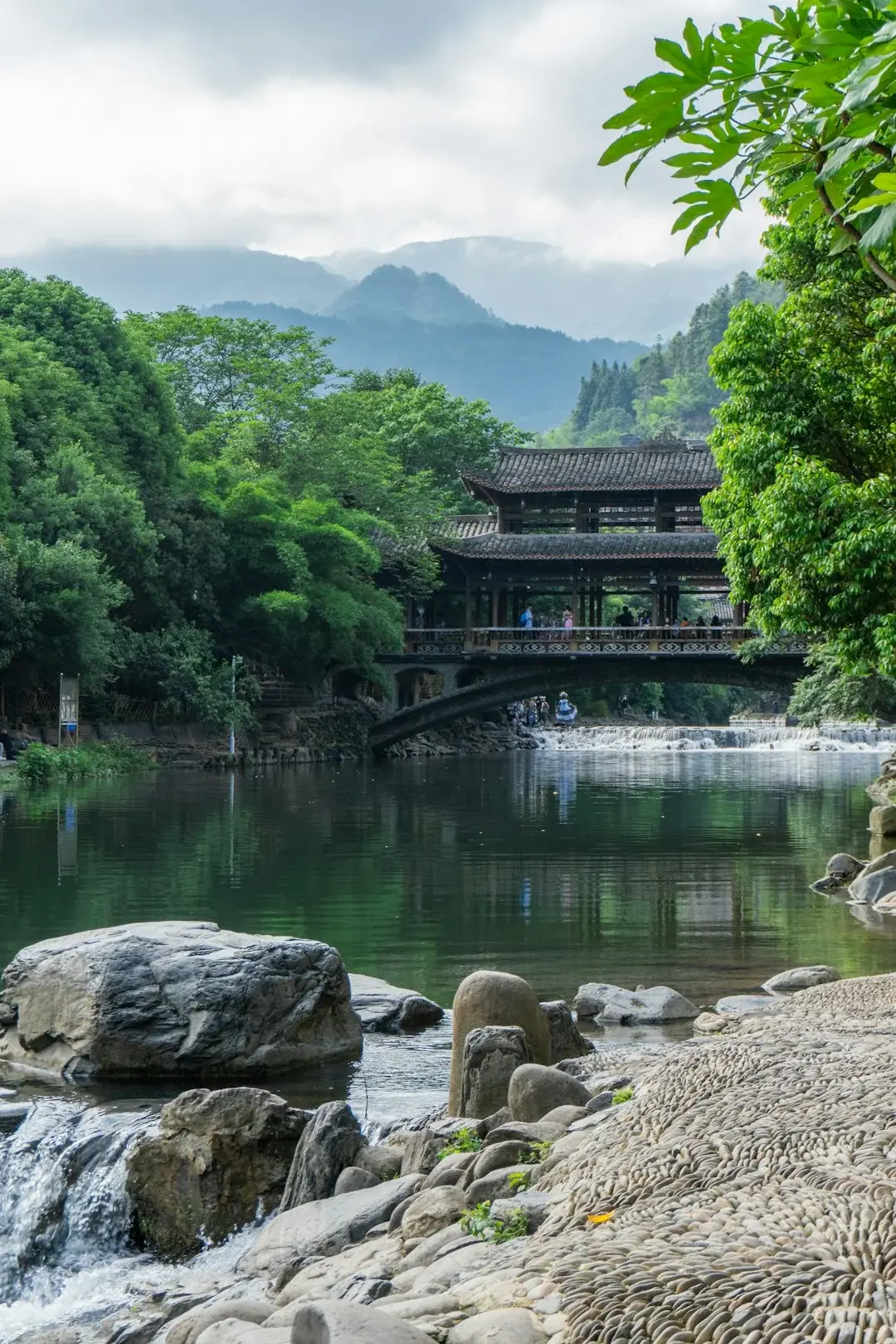 A covered wind-and-rain bridge over a stream in a Dong village in Guizhou