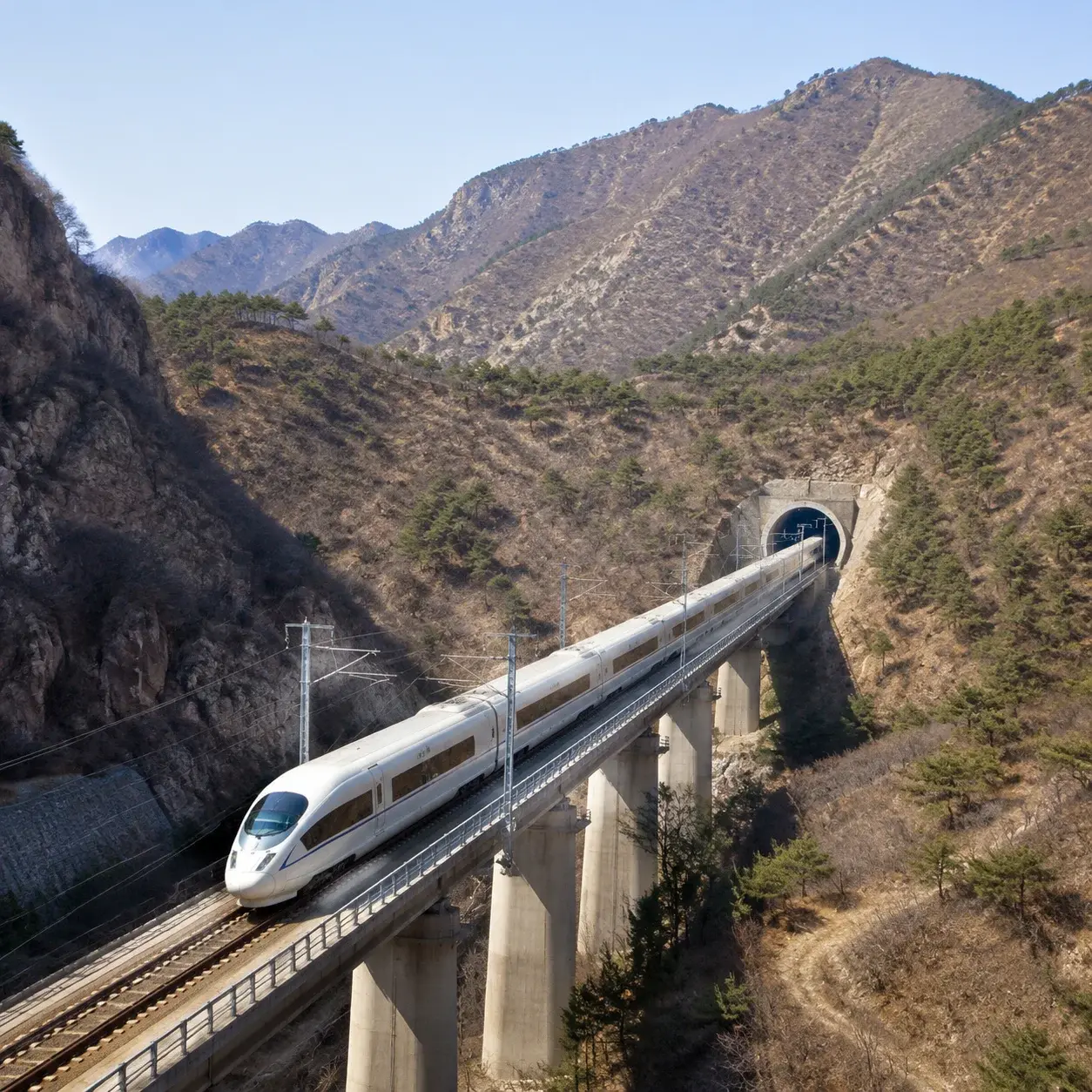 一列高鐵列車行駛在通往八達嶺的鐵路高架橋上,穿越群山
