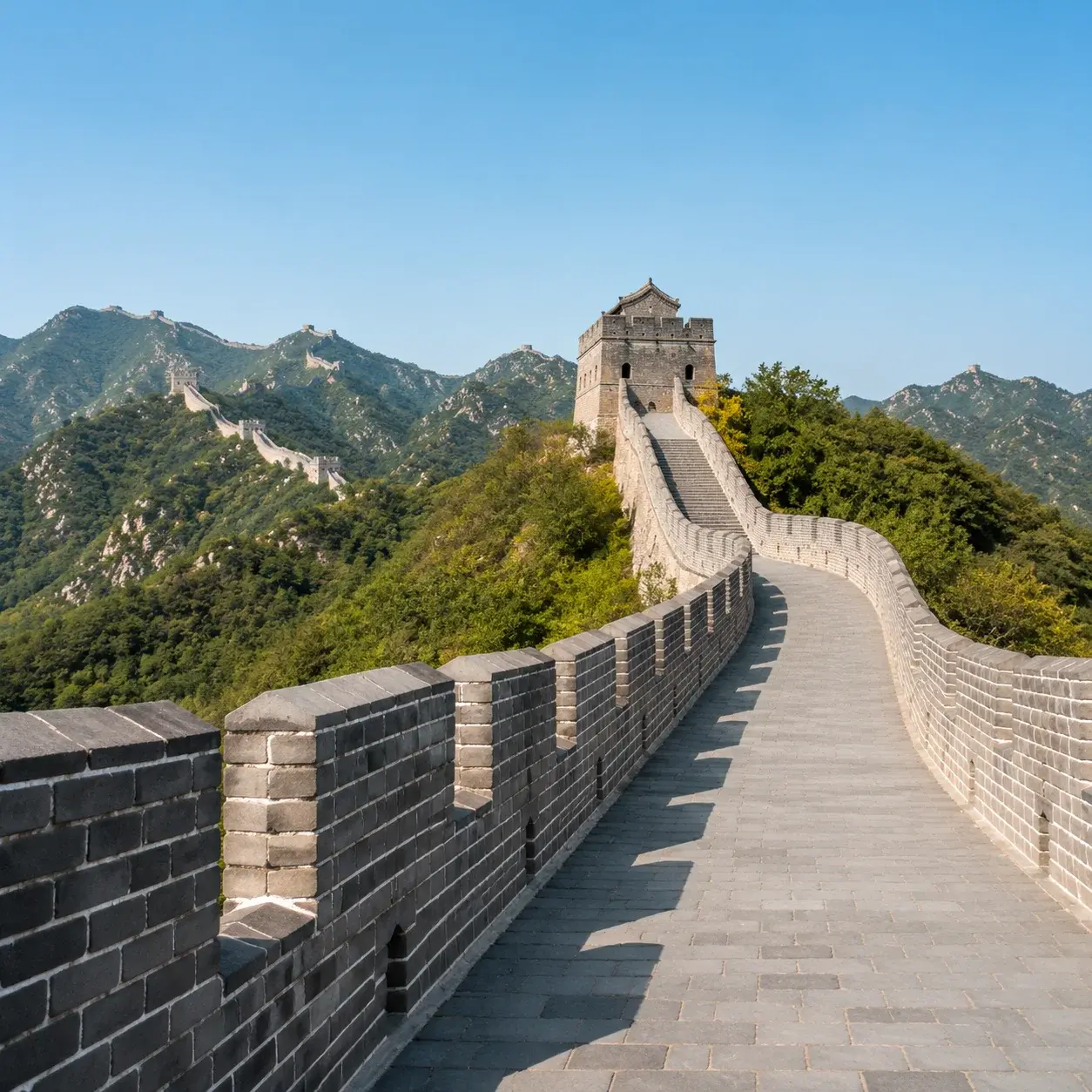 A restored, well-maintained stretch of the Great Wall of China with brick crenellations leading to a watchtower