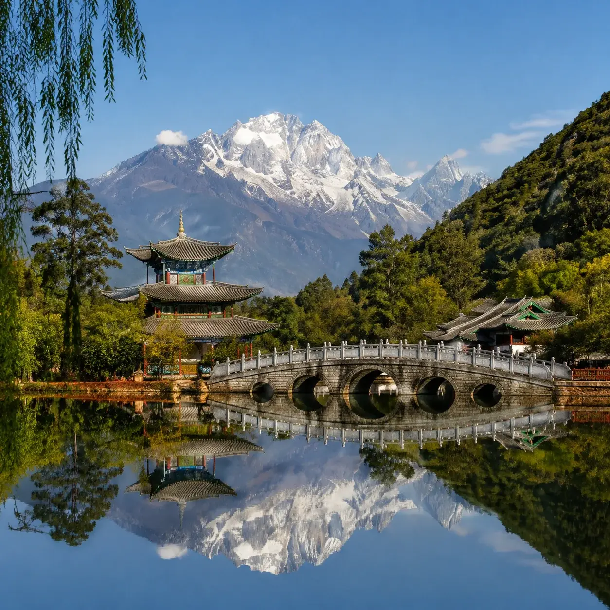 Jade Dragon Snow Mountain reflected in Black Dragon Pool with a stone bridge and pavilion